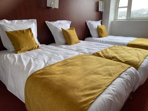 2 camas en una habitación de hotel con almohadas amarillas en HOTEL DE LISIEUX, en Lourdes