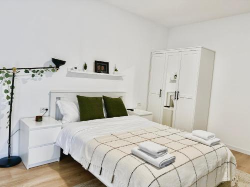 ein weißes Schlafzimmer mit einem großen Bett und grünen Kissen in der Unterkunft Sky Residence Airport Otopeni no 1 in Otopeni