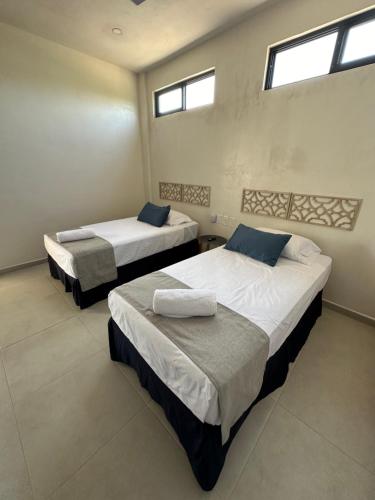 2 camas en una habitación con 2 ventanas en Hotel Casa Prisca, en Coyuca