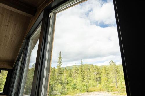 a window with a view of a forest at New, modern, cosy hut close to Norefjell Ski & Spa in Surteberg