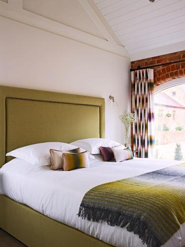 a bedroom with a large bed with white sheets and pillows at The Piggery, South Courtyard in Ledbury