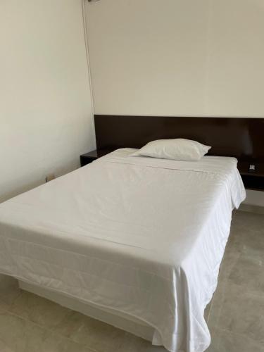 a bed with white sheets and a pillow on it at Hotel Cupules in Mérida