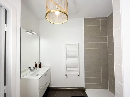 a white bathroom with a sink and a mirror at Suite Helena in Villeurbanne
