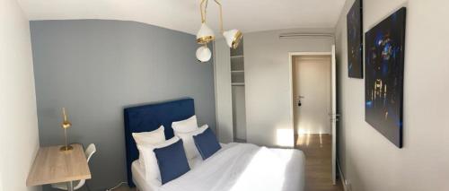 Schlafzimmer mit einem Bett mit blauem Kopfteil und Kissen in der Unterkunft Winnie- Chambre dans un appartement spacieux et charmant in Roanne