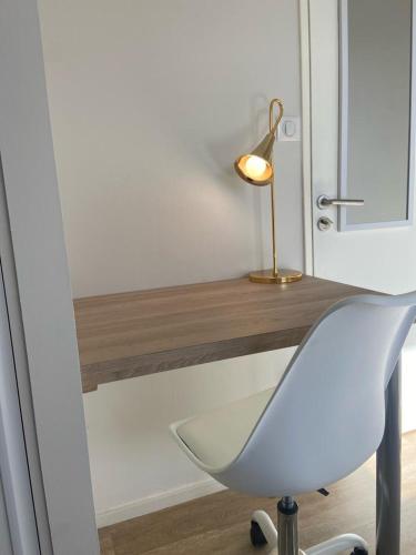 einem weißen Stuhl neben einem Schreibtisch mit einer Lampe in der Unterkunft Winnie- Chambre dans un appartement spacieux et charmant in Roanne