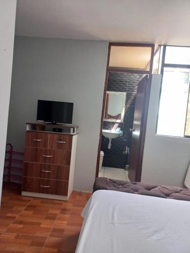 sypialnia z łóżkiem, lustrem i telewizorem w obiekcie Casa de Santitos w mieście Puerto Chicama