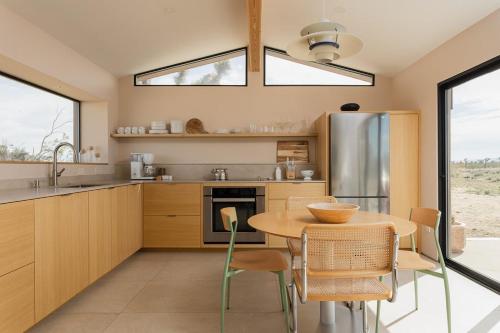 a kitchen with a table and chairs and a kitchen withwindows at Joshua Tree Modern Cabin- Goat Mountain Rising in Landers