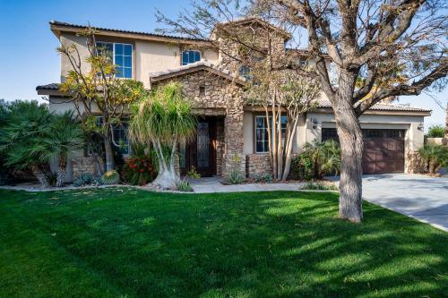 a house with a tree in the yard at Coachella Play - 6BR Multi-Gen Fun Zone and Retreat with free heated pool in Indio