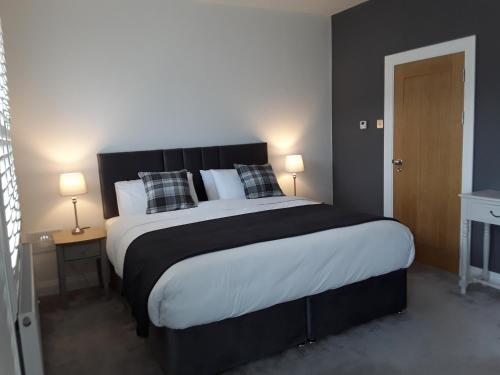 1 dormitorio con 1 cama grande con almohadas blancas y negras en Pairc Na Coille Killarney, en Killarney