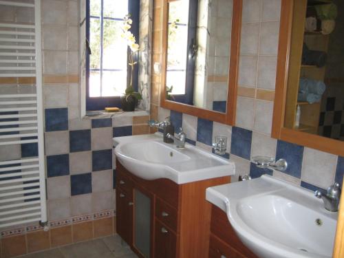 a bathroom with two sinks and two mirrors at Monte das Beatas - Alojamento Local in Beja