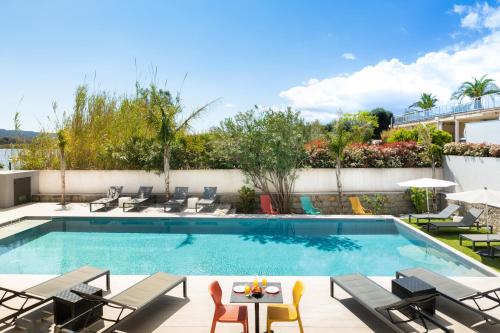 - une piscine avec des chaises et une table à côté d'un bâtiment dans l'établissement Les Roches Blanches, à Porto-Vecchio