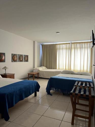 um quarto com 2 camas e uma grande janela em Hotel Armenia Centro em Armênia
