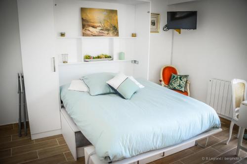 - une chambre blanche avec un lit et des oreillers bleus dans l'établissement STUDIO COSY, à Cabourg