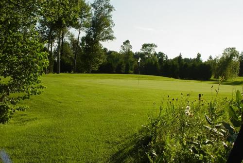 a golf course with a green field with a hole at The Barns of Brighton Near Prince Edward County in Brighton