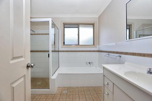 a bathroom with a tub and a sink and a shower at Booner Street Townhouse in Hawks Nest