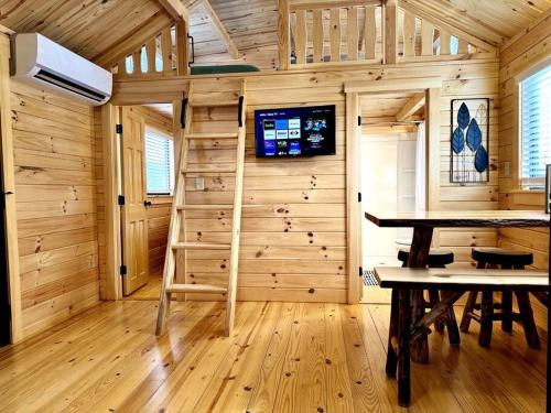 een houten hut met een tafel en een tv aan de muur bij 2 Bedroom Log Cabin on Lake James with Loft- Private Resort Amenities in Marion