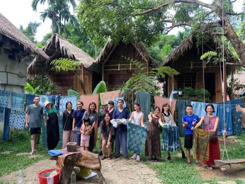 a group of people standing in front of a house at Puluong homestay nacoLodge in Làng Chiêu