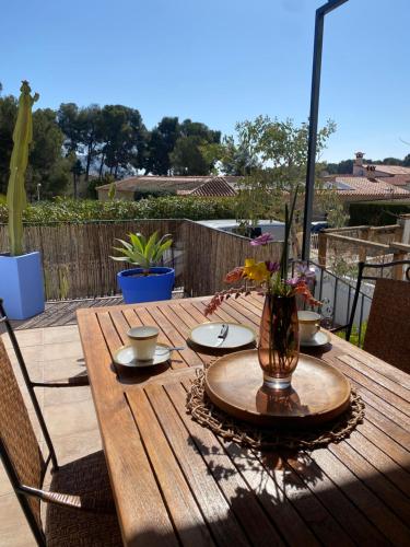 a wooden table with plates and a vase of flowers on it at Bungalow Steps from Moraira in Teulada