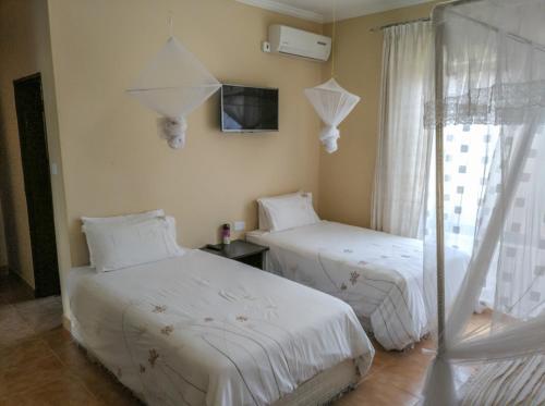 sypialnia z dwoma łóżkami i telewizorem na ścianie w obiekcie KALIYANGILE GUEST HOUSE w mieście Lusaka