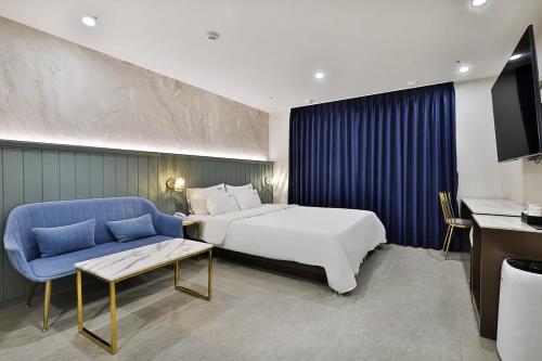 um quarto de hotel com uma cama e um sofá azul em Hotel Palace Gyeongju em Gyeongju