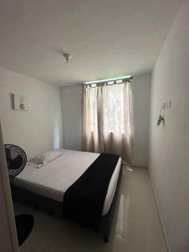 a small bedroom with a bed and a window at Hospedaje Los Cedros in Girón