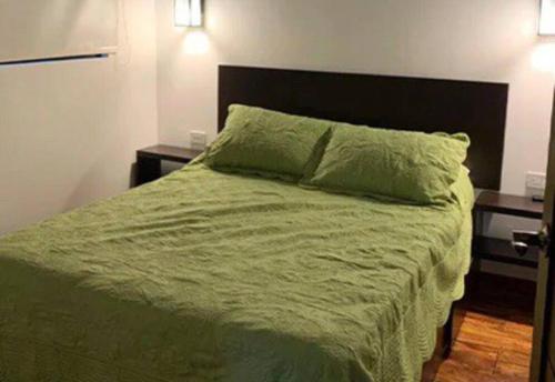 a bedroom with a green bed with two night stands at Cabaña Bosquemar 1 in Agujas