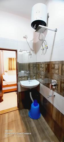 a bathroom with a sink and a light on the wall at Shiv Niketan Guest House 200mtr from Shri Ram mandir in Ayodhya