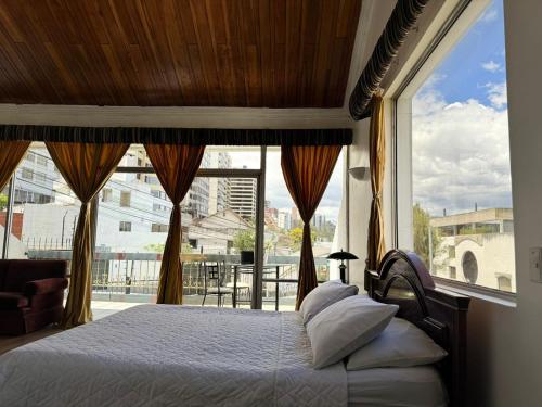 1 dormitorio con cama y ventana grande en Suites & Hotel Gonzalez Suarez en Quito