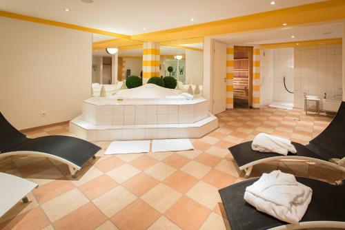 a large bathroom with a tub and a large room with chairs at Hotel Residenz in Bocholt