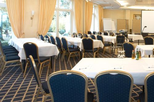 a room filled with tables and chairs with white tablecloths at Hotel Residenz in Bocholt