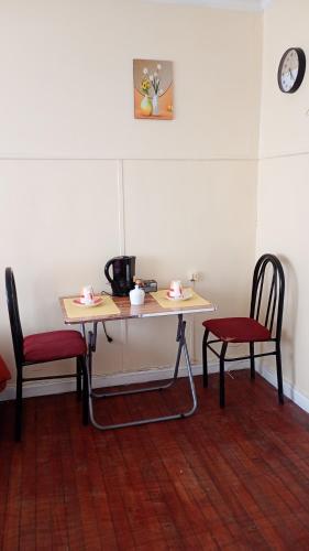 una mesa con dos sillas y una mesa con tazas. en hostal RV en Temuco