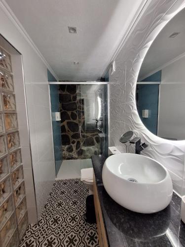 a bathroom with a large white sink and a shower at Casa do Poço in Santa Bárbara