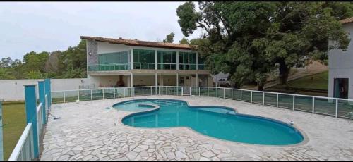 a house with a swimming pool in front of a house at Chácara Rosa do Deserto in Vila Velha