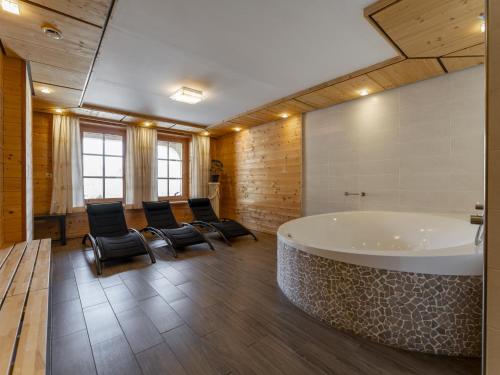 La salle de bains spacieuse est pourvue d'une grande baignoire et de chaises. dans l'établissement Chalet Kristall I, à Grossarl