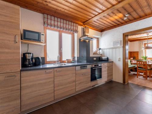 a kitchen with wooden cabinets and a television on the wall at Chalet Kristall II in Grossarl