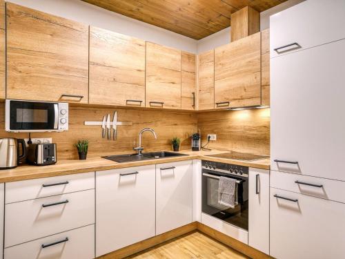 a kitchen with white cabinets and wooden walls at Bergliebe in Kappl