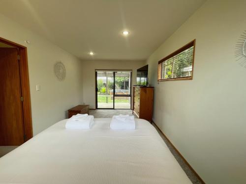 a bedroom with a bed with two white towels on it at Oneroa Spa Retreat- Waiheke Escapes in Blackpool