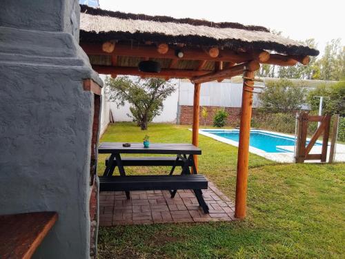 a picnic table under a gazebo next to a pool at Hospedaje El Ciruelo in Alta Gracia