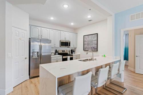 a kitchen with white cabinets and a large island with chairs at The Epic London Vista Cay Orlando Next to the club in Orlando