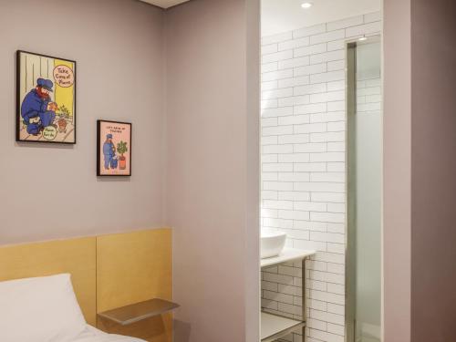 a bathroom with a bed and a sink and a mirror at Markers Hostel in Gangneung