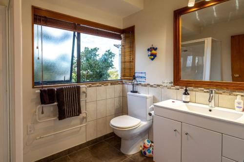a bathroom with a toilet and a sink and a window at Oneroa Spa Retreat- Waiheke Escapes in Blackpool