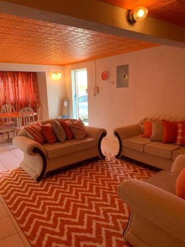 a living room with two couches and a rug at Lovely 2 bedroom condo with WiFi in a quiet area, 7-10 minutes away from both the airport and Oistins in Christ Church