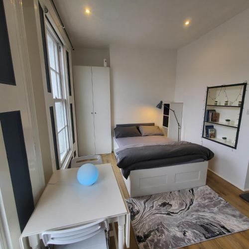 um pequeno quarto com 2 camas e uma mesa em London Oasis Studio Apartment em Londres