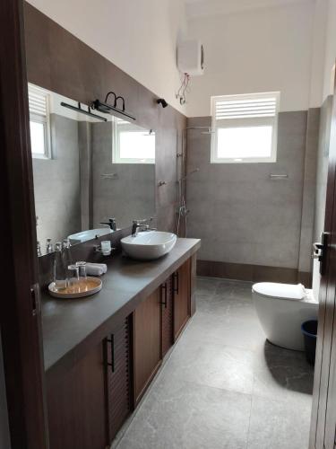 La salle de bains est pourvue de 2 lavabos, d'une baignoire et de toilettes. dans l'établissement Villa Vyoma, à Talpe
