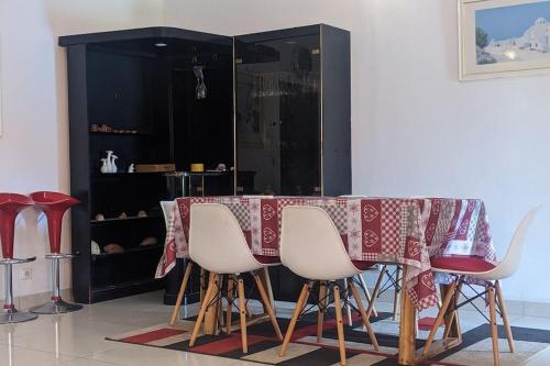 Élégante villa avec jardin+bar في لوميه: طاولة غرفة طعام مع كراسي بيضاء وخزانة سوداء