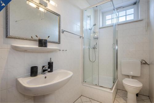 La salle de bains blanche est pourvue d'un lavabo et d'une douche. dans l'établissement Villa Linde FeWo 1, à Ahlbeck
