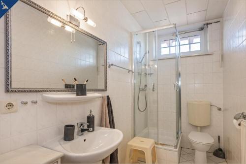 ein weißes Bad mit einem Waschbecken und einer Dusche in der Unterkunft Villa Linde FeWo 2 in Ahlbeck