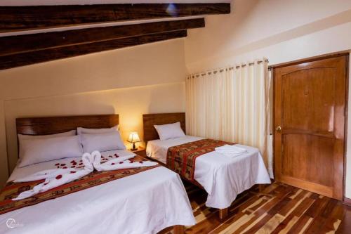 a bedroom with two beds with white sheets at MACHUPICCHUROYAL B y B in Machu Picchu