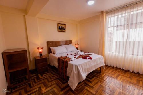 a bedroom with a bed with a white blanket and a window at MACHUPICCHUROYAL B y B in Machu Picchu