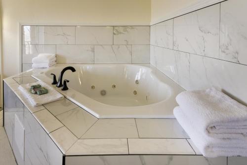 a white bath tub in a bathroom with white tiles at Best Western Branson Inn and Conference Center in Branson